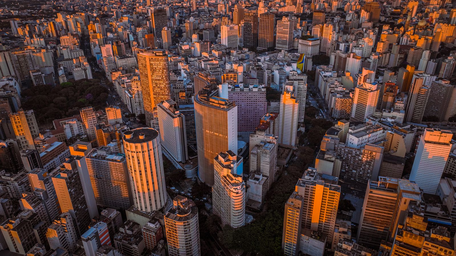 Skyline de centro financeiro ao anoitecer com torres de vidro iluminadas, representando o cerco regulatório do Banco Central às corretoras de cripto no Brasil