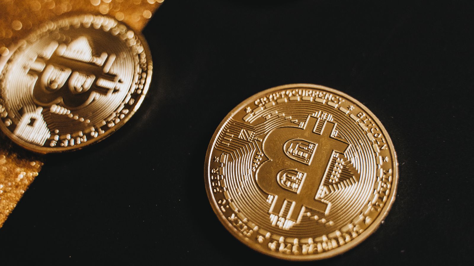 Moedas de bitcoin sobre cédulas de real, simbolizando o bitcoin a US$ 77 mil e a proteção do patrimônio em reais
