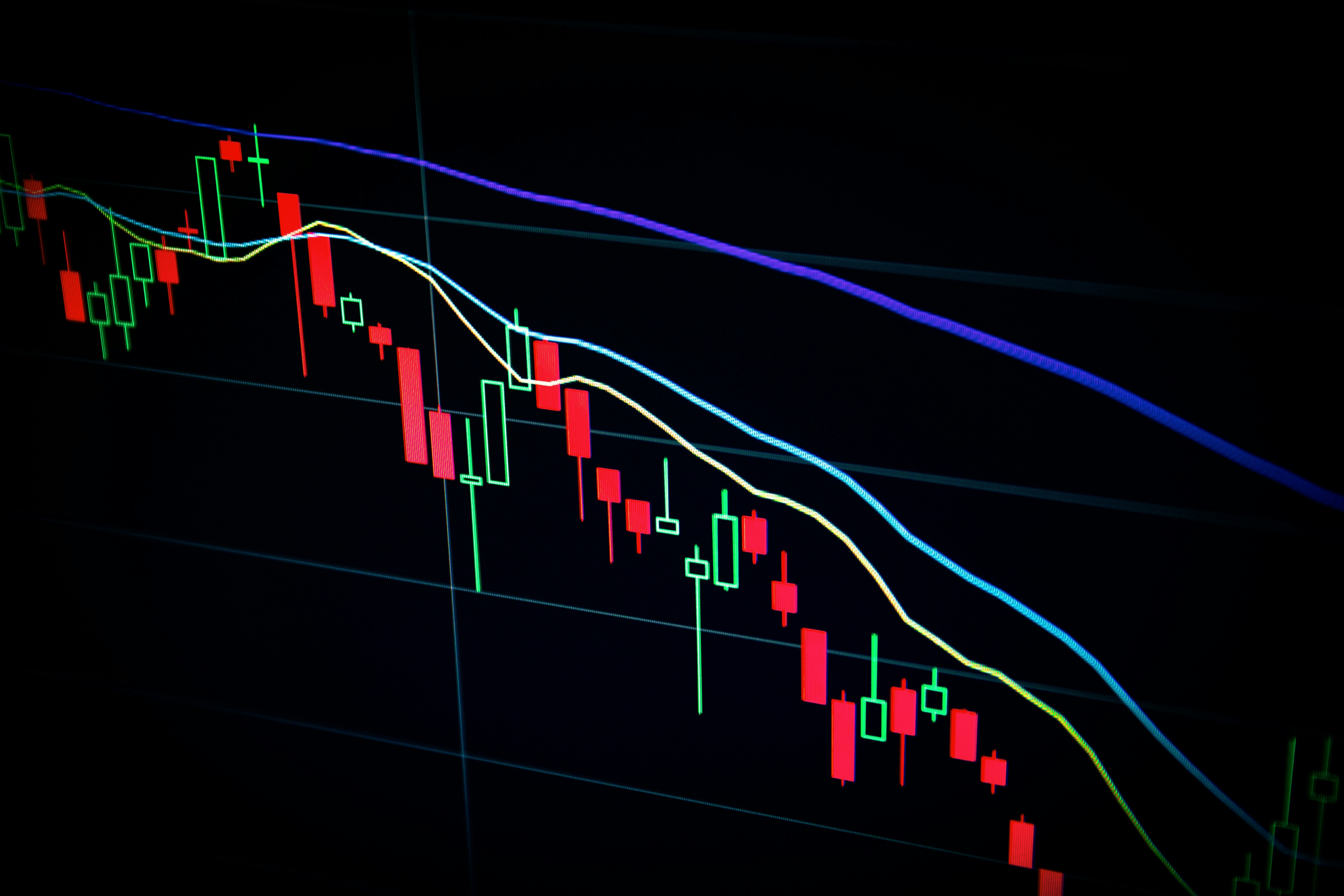Gráfico de candlestick do Bitcoin em tela escura de trading, simbolizando a defesa do nível de US$ 77 mil em meio à guerra entre EUA e Irã e à virada hawkish do Fed