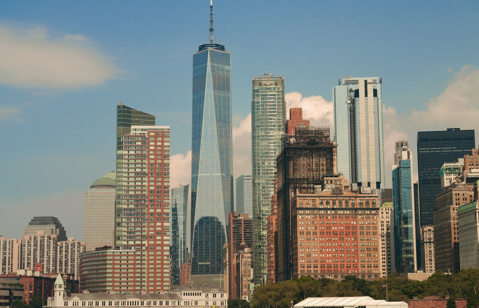 Arranha-céus de Manhattan, em Nova York, com o One World Trade Center em destaque sob céu azul.