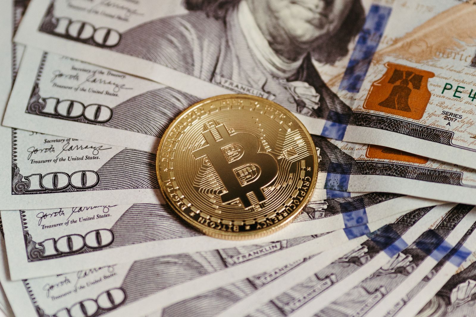 Moeda representativa de Bitcoin sobre notas de dólar americano.